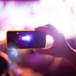 People taking photographs with smart phone during Live music concert and crowd in background